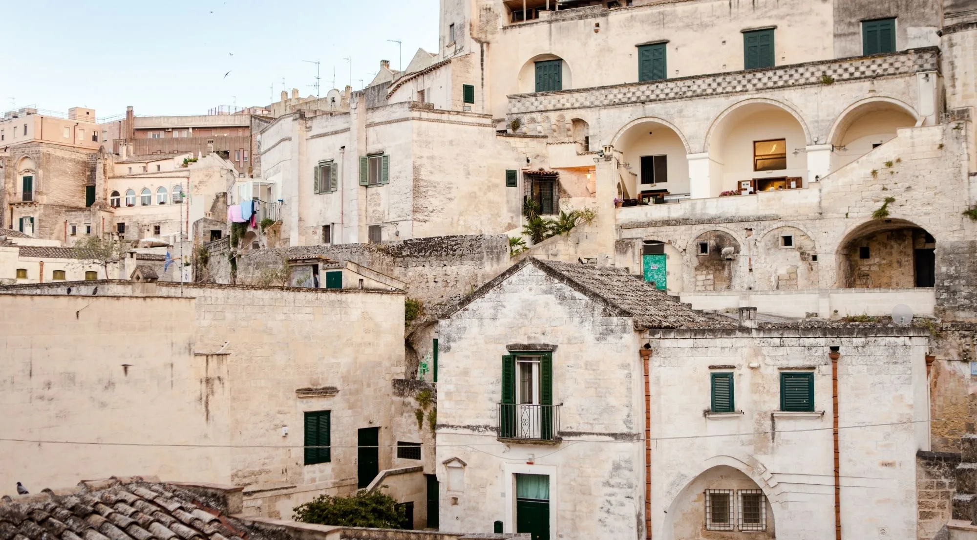 White stone facades with arched loggias and green shutters in the Sassi