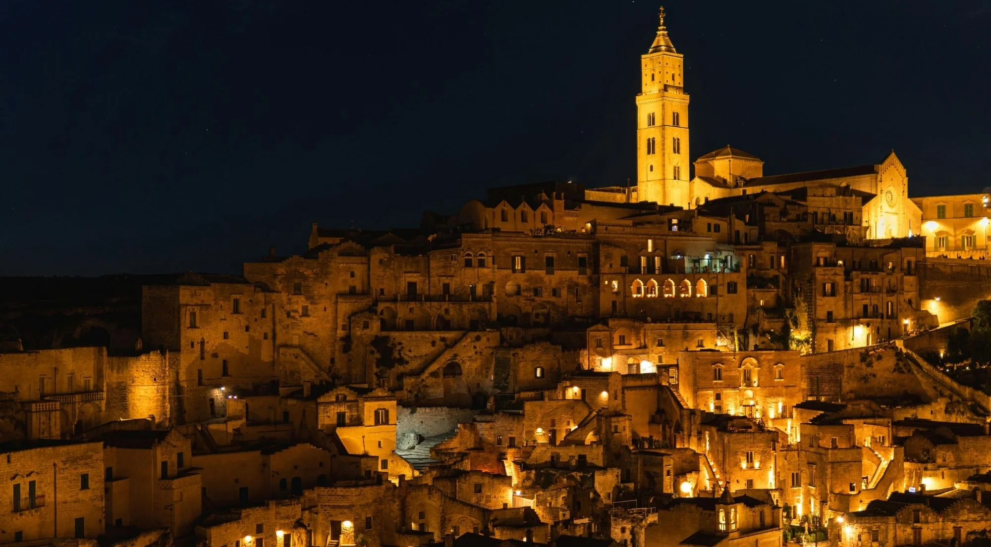 The Sassi lit up after dark, with the floodlit cathedral tower above the old cave town