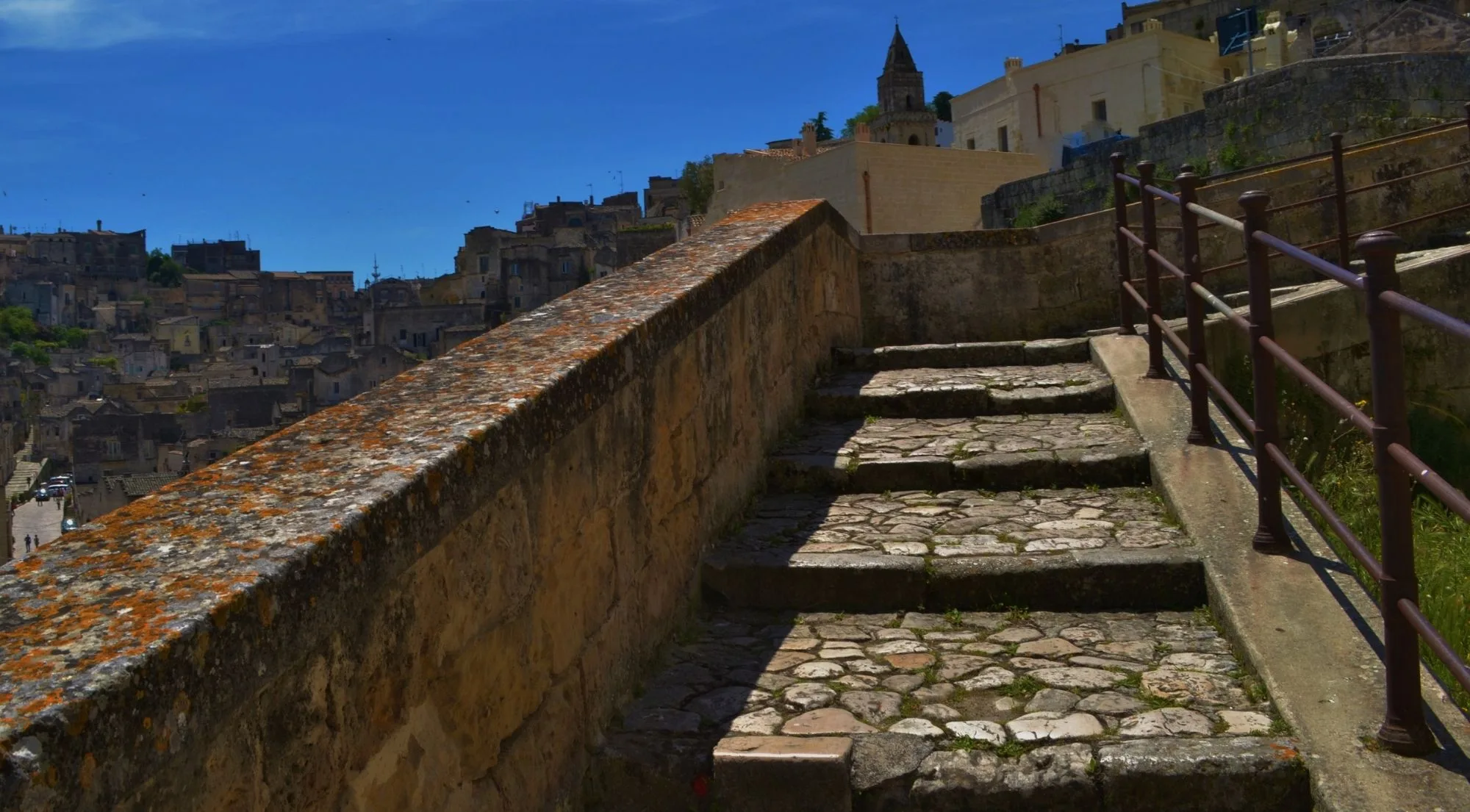 Worn stone steps with an iron railing climbing through the Sassi at dusk