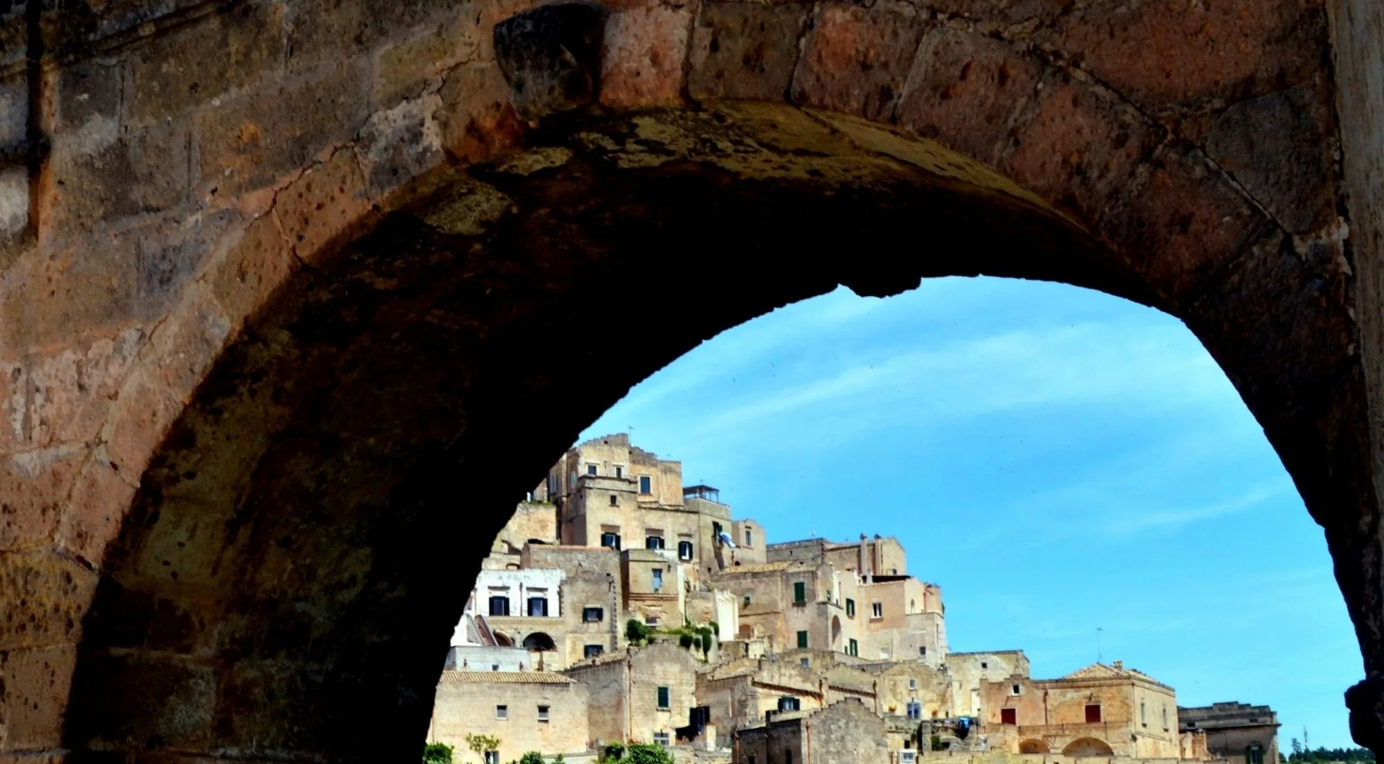 Pale stone houses of the Sassi seen through a dark stone archway