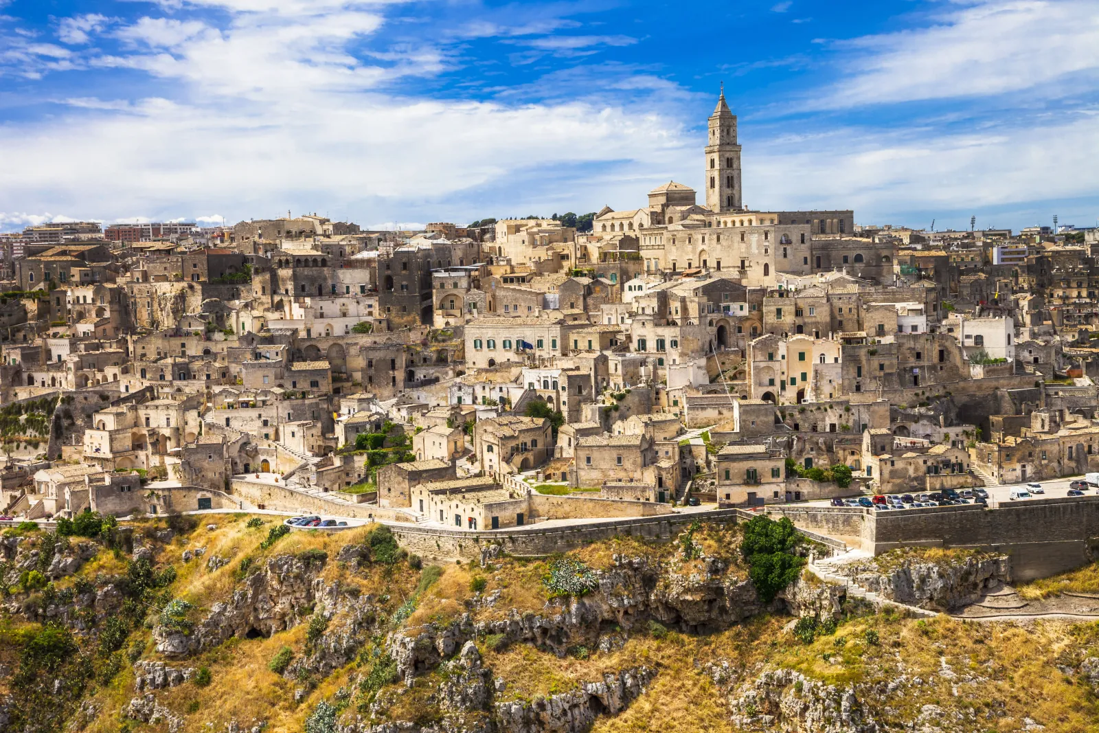 Aerial view of Matera's Sassi above the Gravina gorge, with the cathedral bell tower at the top of town.