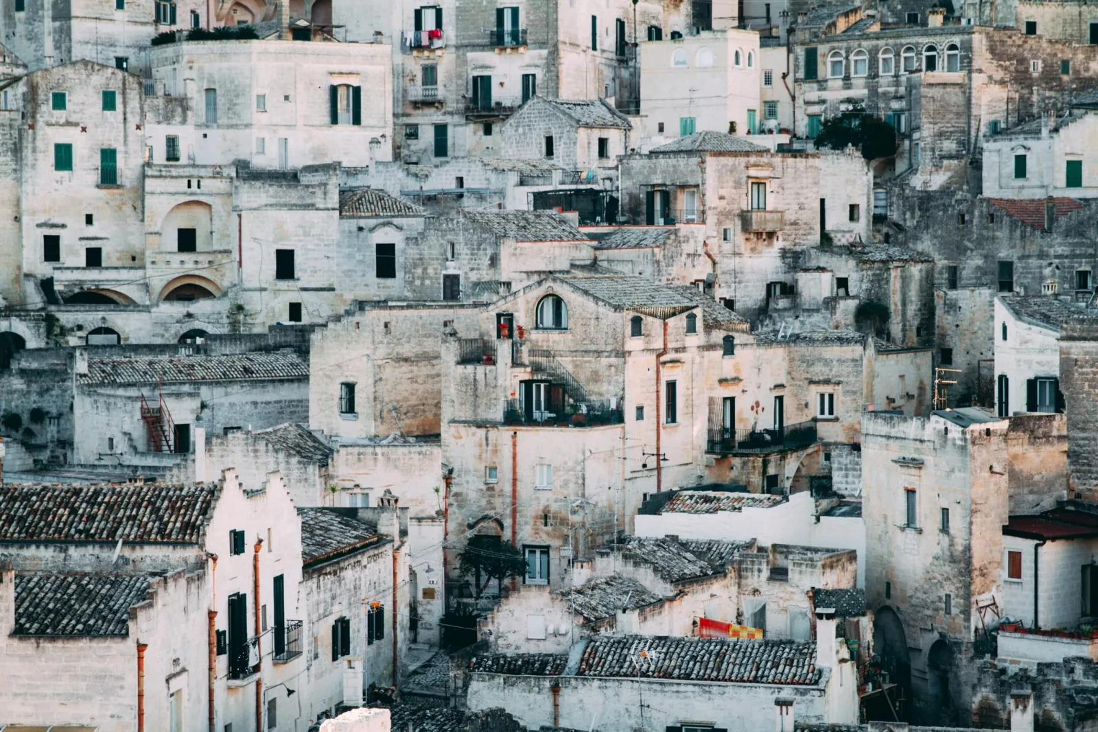 Close view of terraced stone houses with tiled roofs and small windows climbing the hillside of the Sassi.