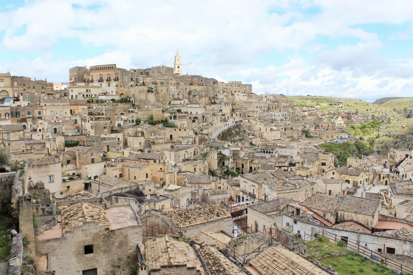 Terracotta and stone rooftops of the Sassi di Matera spread across the hillside, with the cathedral tower on the skyline.