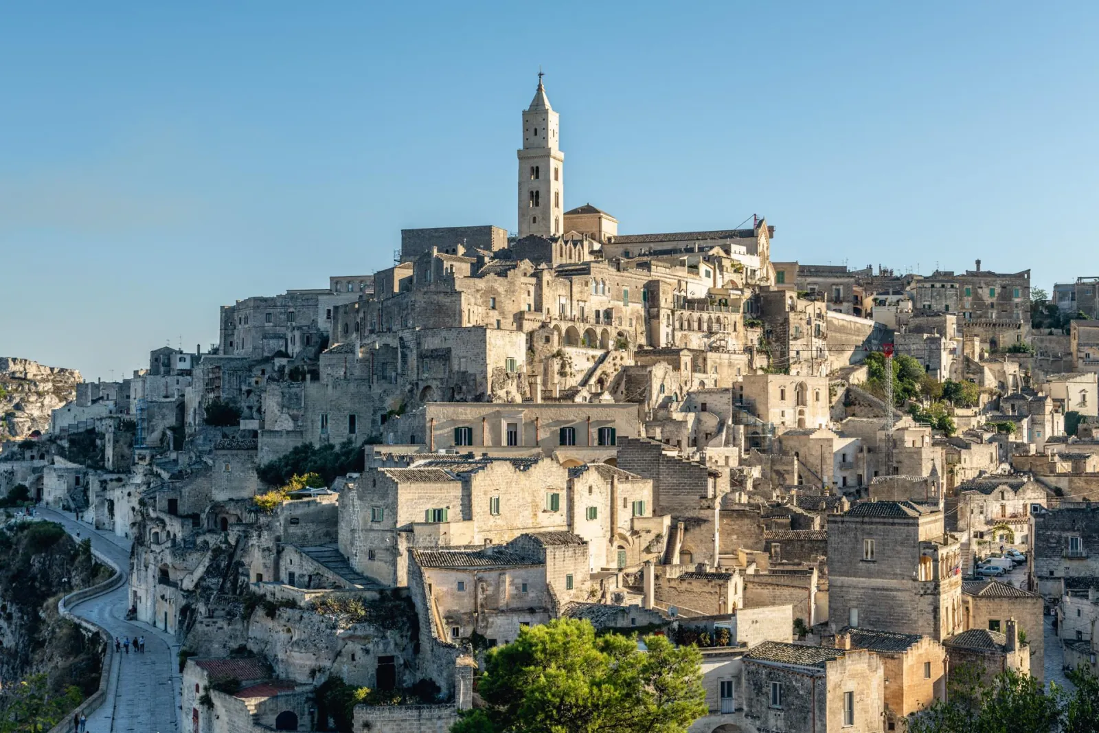 The Sassi di Matera rising up the hillside to the cathedral bell tower, with a road curving below.